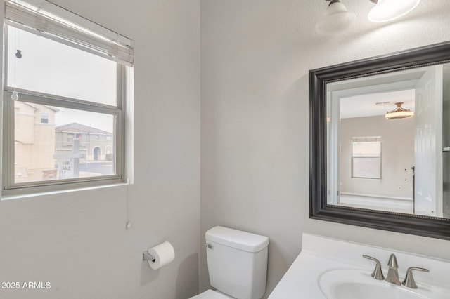 half bathroom with a sink, toilet, and a healthy amount of sunlight