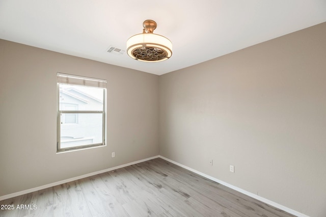 unfurnished room featuring visible vents, light wood-style floors, and baseboards