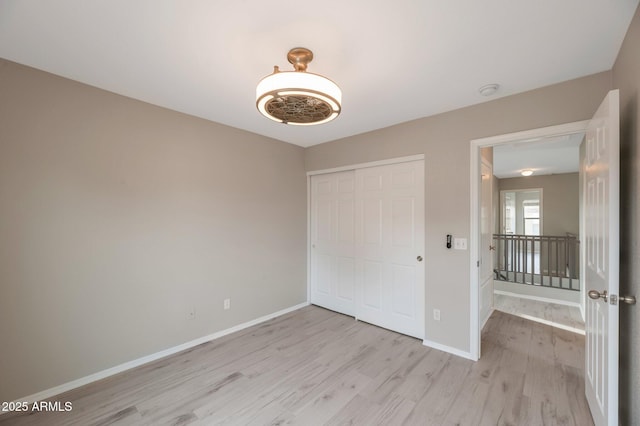 unfurnished bedroom with light wood-type flooring, baseboards, and a closet