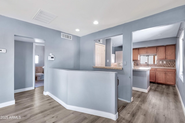 kitchen with decorative backsplash, wood-type flooring, and kitchen peninsula