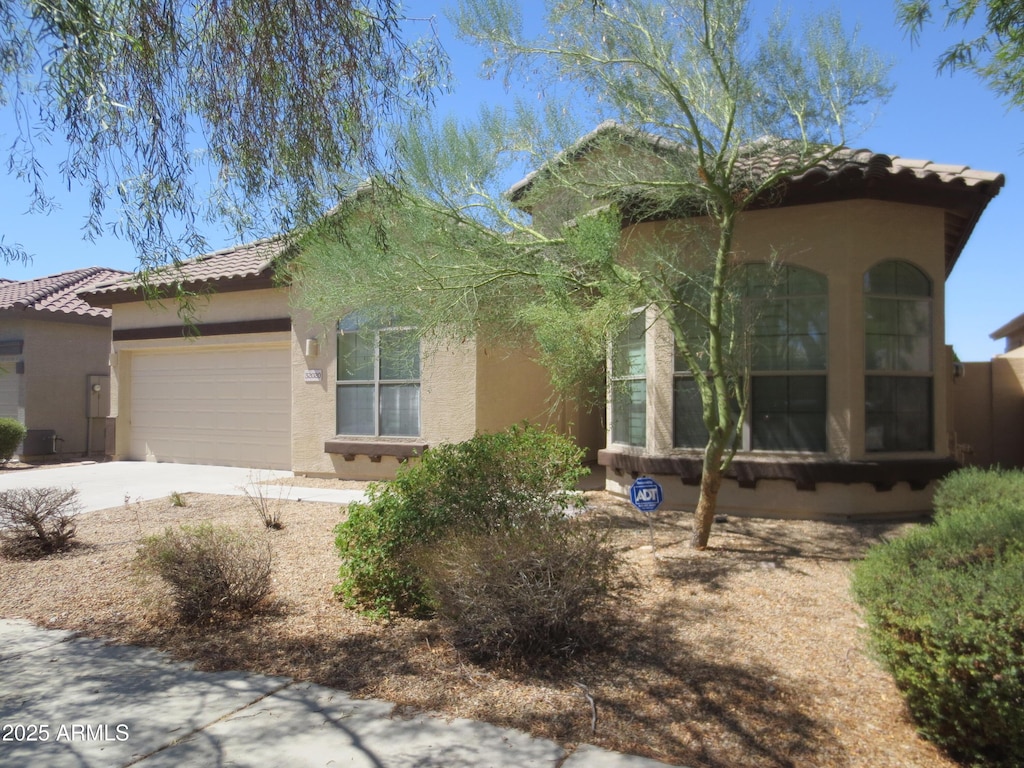 view of front of property featuring concrete driveway, a tiled roof, a garage, and stucco siding