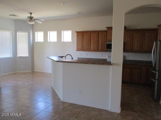 32020 N 23rd Ave, Phoenix, AZ 85085 - kitchen with appliances with stainless steel finishes, a ceiling fan, dark countertops, brown cabinetry, and light tile patterned floors