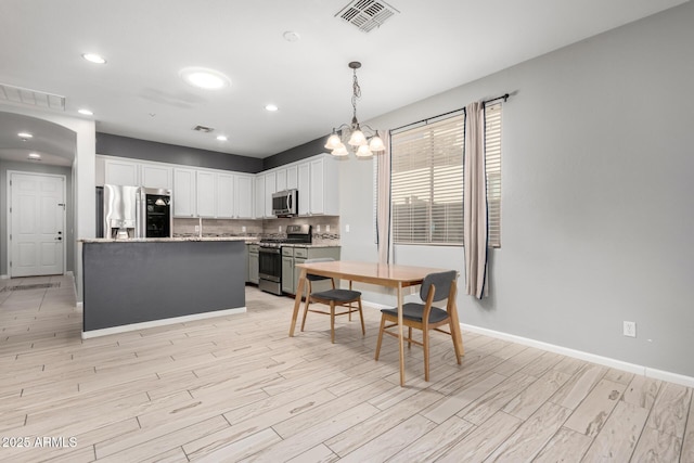 kitchen featuring stainless steel appliances, tasteful backsplash, a kitchen island, pendant lighting, and white cabinets