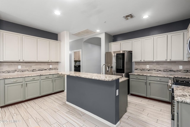 kitchen with light stone counters, a center island, stainless steel appliances, and tasteful backsplash