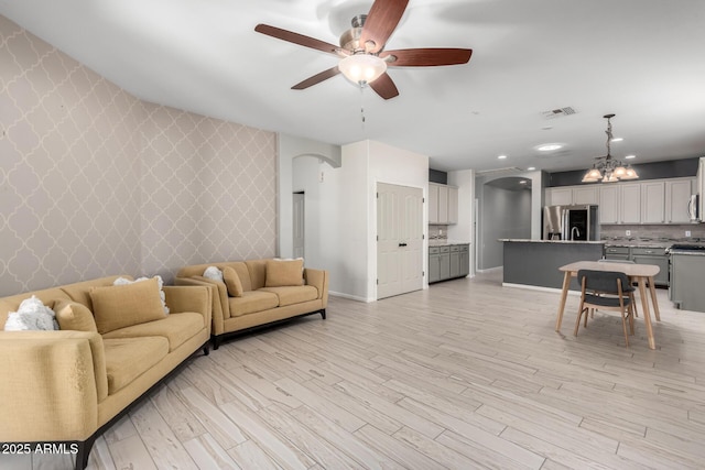 living room with light hardwood / wood-style floors and ceiling fan with notable chandelier