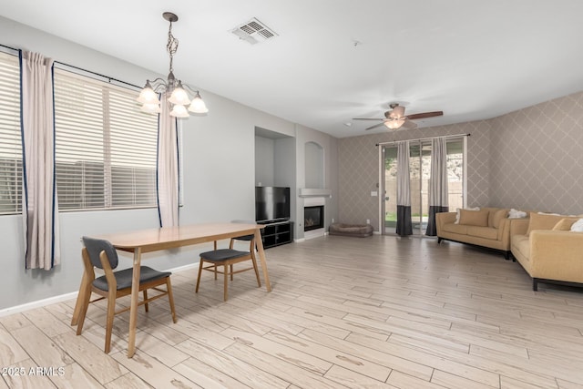 dining room with ceiling fan with notable chandelier and light hardwood / wood-style flooring