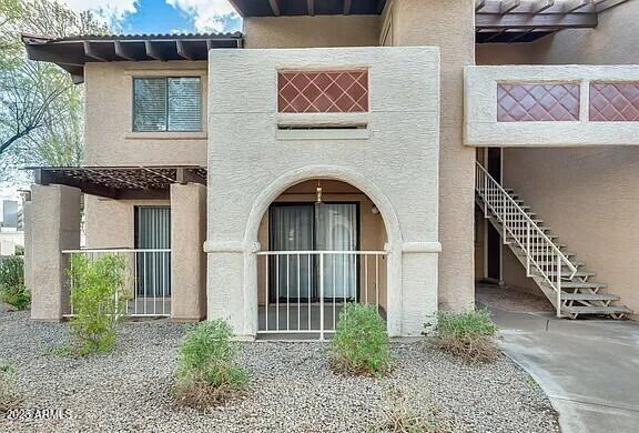 rear view of property featuring stairway and stucco siding