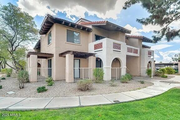 mediterranean / spanish home with a tiled roof, fence, a balcony, and stucco siding