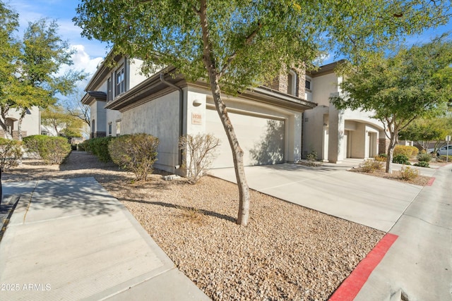 view of home's exterior with an attached garage, concrete driveway, and stucco siding