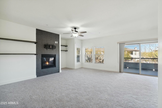 unfurnished living room with carpet, a large fireplace, ceiling fan, and baseboards