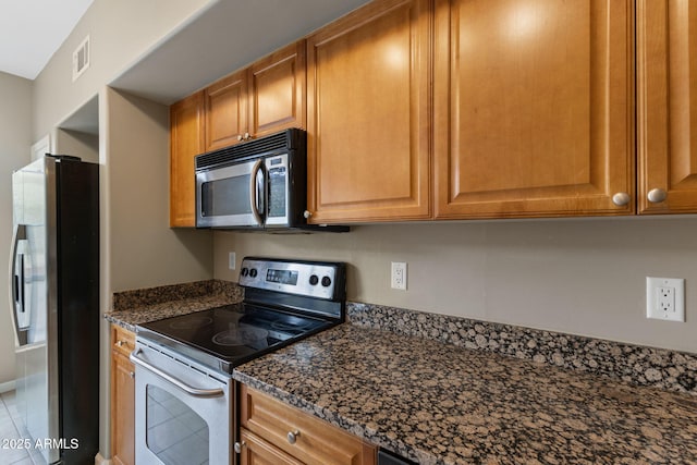 kitchen featuring appliances with stainless steel finishes and dark stone counters