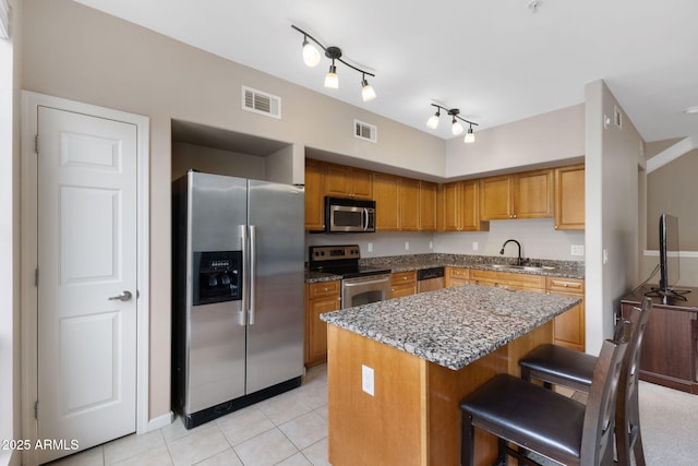 kitchen featuring sink, light tile patterned floors, a breakfast bar area, stainless steel appliances, and a kitchen island