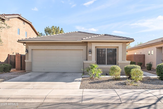 view of front of home with a garage, concrete driveway, a tile roof, fence, and stucco siding