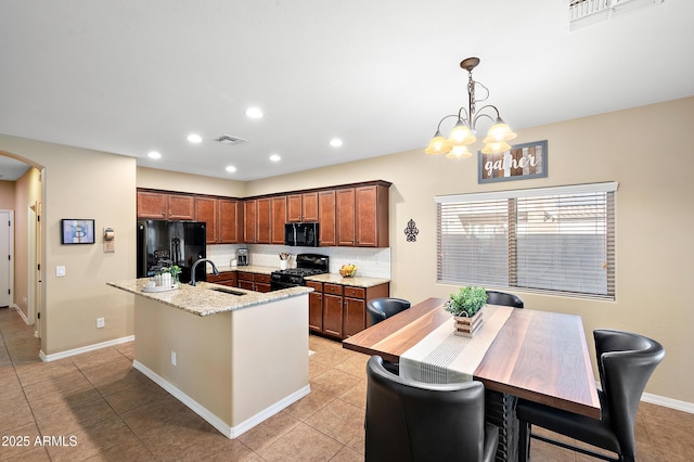 kitchen featuring arched walkways, a kitchen island with sink, visible vents, black appliances, and tasteful backsplash