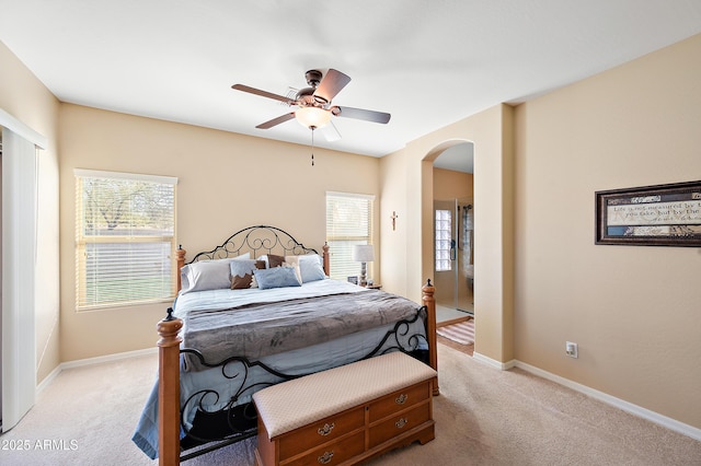 bedroom with arched walkways, multiple windows, baseboards, and light colored carpet