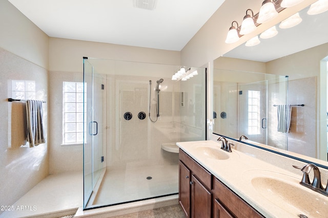 bathroom featuring double vanity, a stall shower, a sink, and visible vents