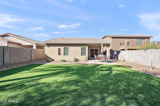 rear view of property with a yard, a patio area, a fenced backyard, and stucco siding