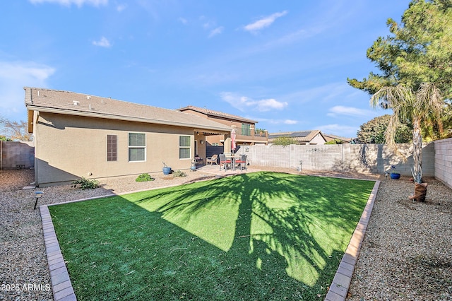 back of property with a yard, a patio area, a fenced backyard, and stucco siding