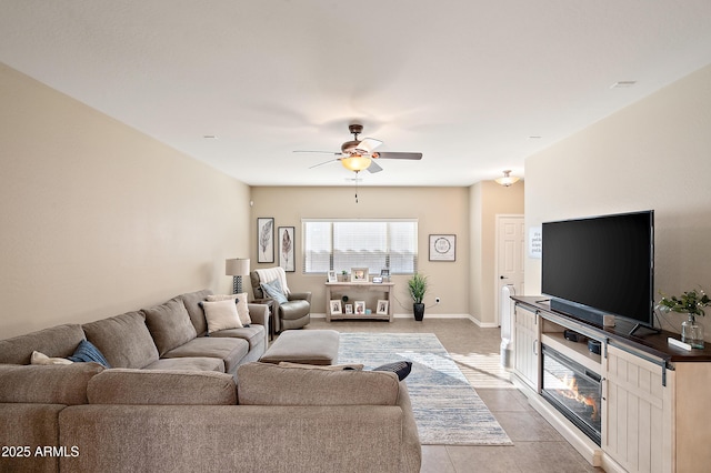 living area with ceiling fan, baseboards, and light tile patterned flooring