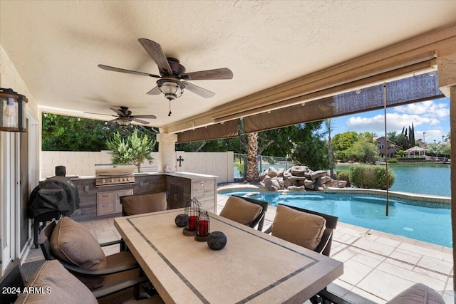 view of patio with an outdoor kitchen, a water view, area for grilling, and a fenced in pool