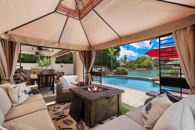 view of swimming pool with a water view, an outdoor living space with a fire pit, and a patio area