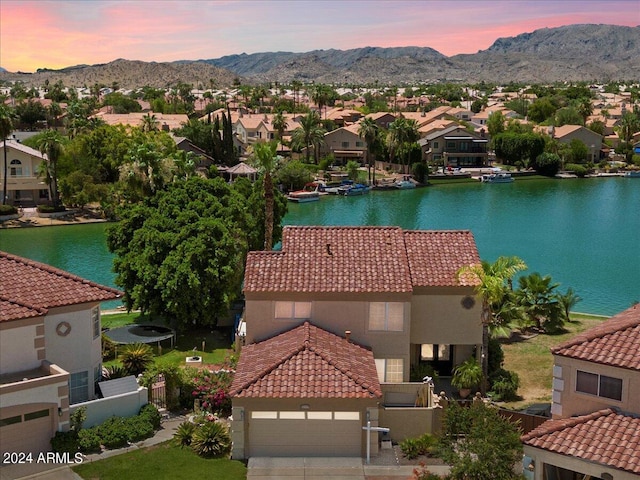 aerial view at dusk featuring a water and mountain view