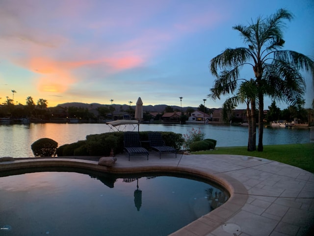 pool at dusk featuring a water view