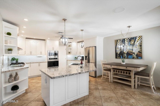 kitchen with light stone countertops, stainless steel appliances, sink, white cabinets, and hanging light fixtures