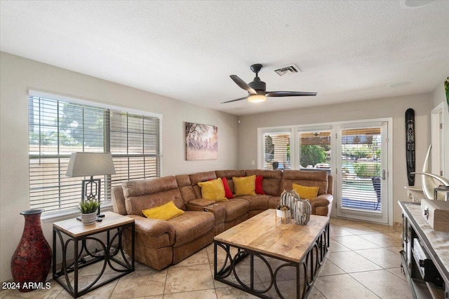 living room with ceiling fan, light tile patterned flooring, and a textured ceiling