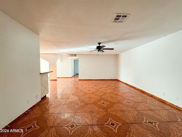 tiled empty room with a textured ceiling and ceiling fan