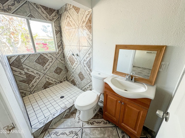 bathroom with tiled shower, vanity, and toilet