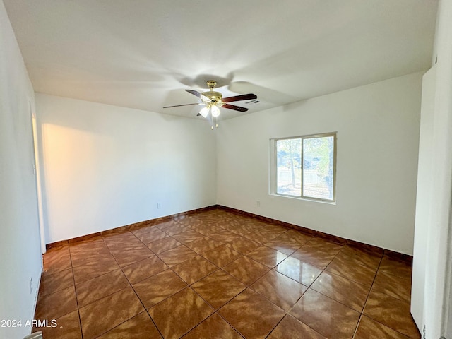 spare room with dark tile patterned floors and ceiling fan