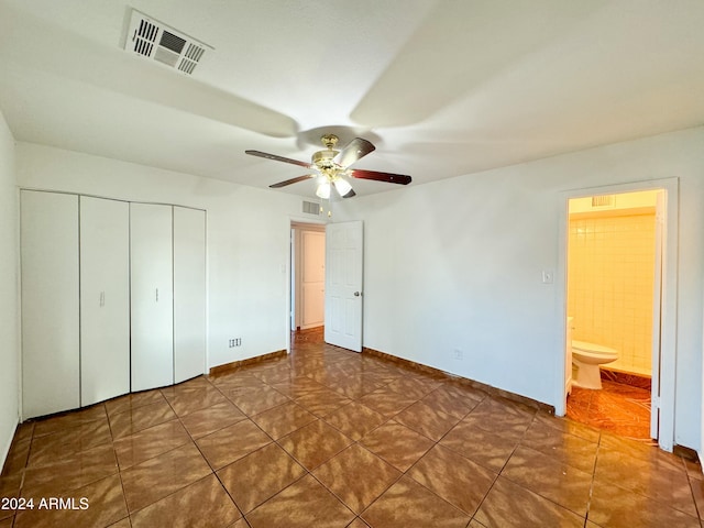 unfurnished bedroom featuring ensuite bath, ceiling fan, and dark tile patterned floors