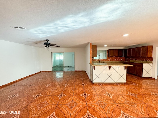 kitchen featuring sink, tile patterned flooring, kitchen peninsula, a textured ceiling, and a kitchen bar