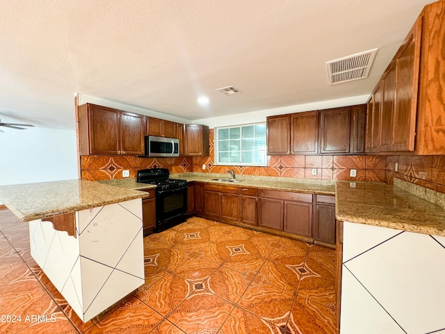 kitchen featuring kitchen peninsula, backsplash, black range oven, and sink