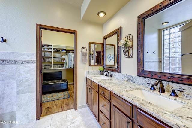 bathroom featuring double vanity, a sink, and a walk in closet