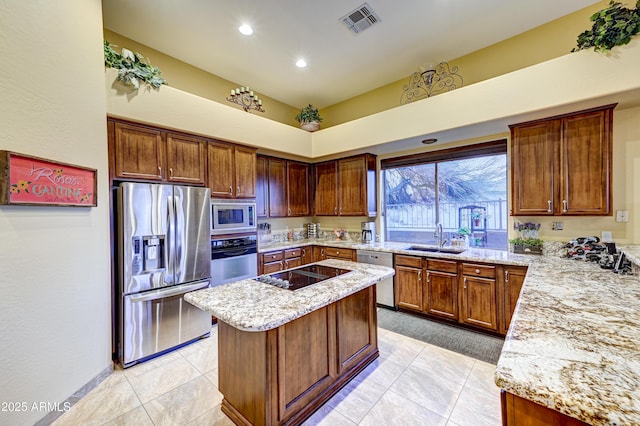 kitchen featuring stainless steel appliances, light stone counters, a sink, and visible vents