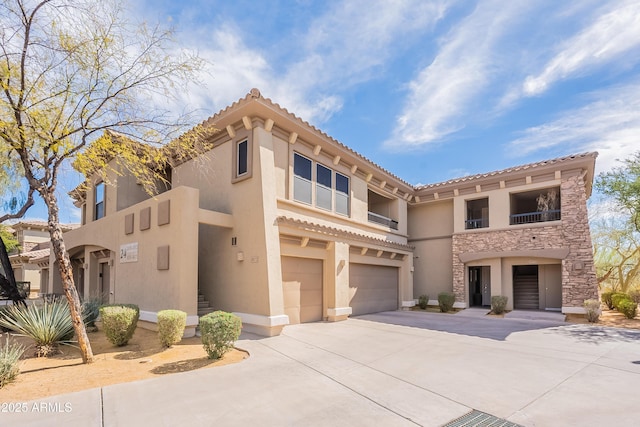 mediterranean / spanish home with stone siding, driveway, an attached garage, and stucco siding