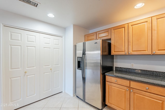 kitchen featuring light tile patterned floors, visible vents, dark stone countertops, stainless steel refrigerator with ice dispenser, and recessed lighting