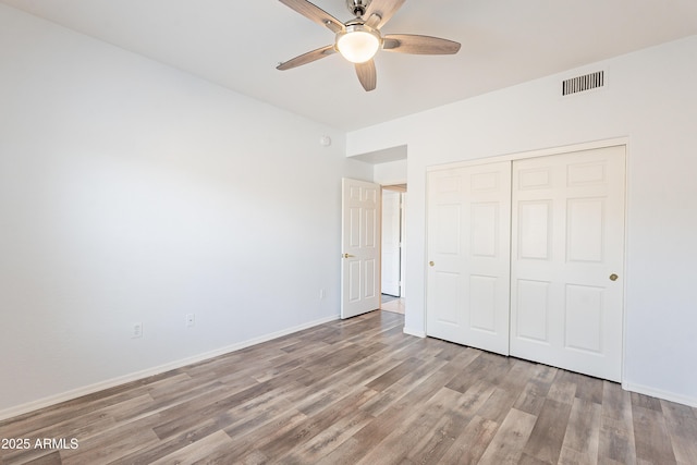 unfurnished bedroom featuring a closet, visible vents, ceiling fan, light wood-type flooring, and baseboards