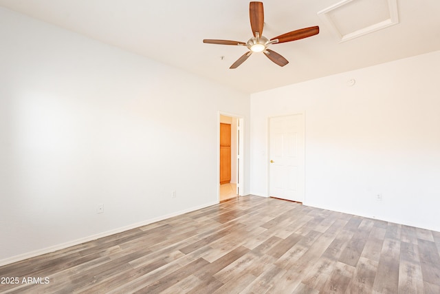 empty room with wood finished floors, attic access, and baseboards