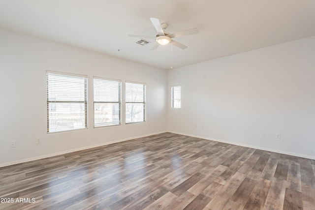 spare room featuring dark wood-style floors, visible vents, ceiling fan, and baseboards