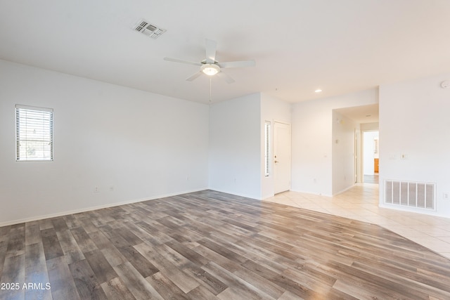 empty room with light tile patterned floors, ceiling fan, visible vents, and baseboards