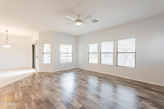 unfurnished room with baseboards, ceiling fan, visible vents, and wood finished floors