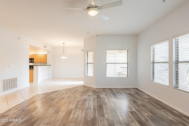 unfurnished living room featuring light wood-style flooring, visible vents, ceiling fan, and baseboards