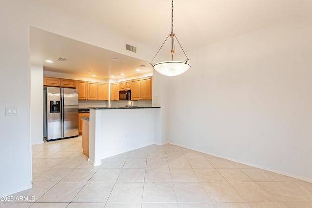 kitchen with stainless steel fridge with ice dispenser, dark countertops, a peninsula, black microwave, and pendant lighting