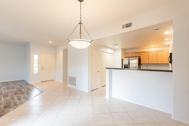 interior space featuring dark countertops, visible vents, decorative light fixtures, and stainless steel fridge with ice dispenser