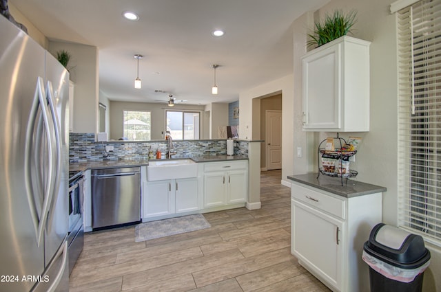 kitchen featuring light hardwood / wood-style flooring, stainless steel appliances, hanging light fixtures, and white cabinetry