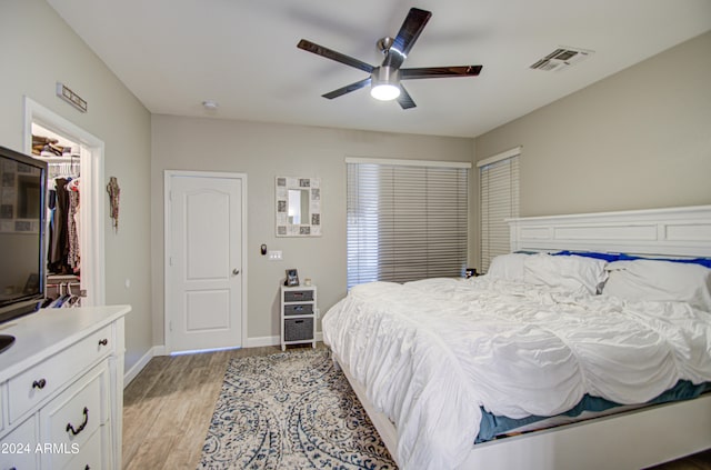 bedroom featuring ceiling fan, a walk in closet, a closet, and light wood-type flooring