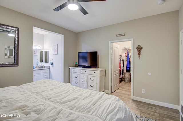 bedroom with a spacious closet, a closet, ensuite bathroom, light hardwood / wood-style floors, and ceiling fan